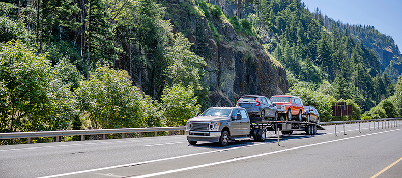 open trailer hauling vehicles on picturesque road