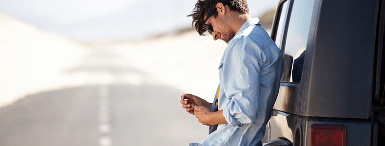 Man with phone leaning on van