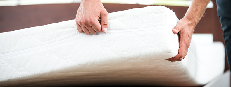 person lifting a mattress as they prepare to ship household goods