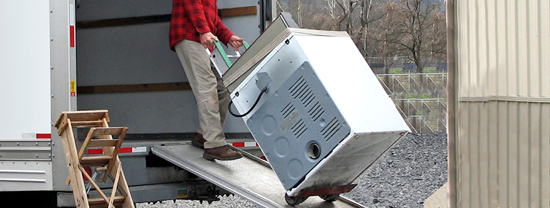 Person moving an appliance into truck for transport