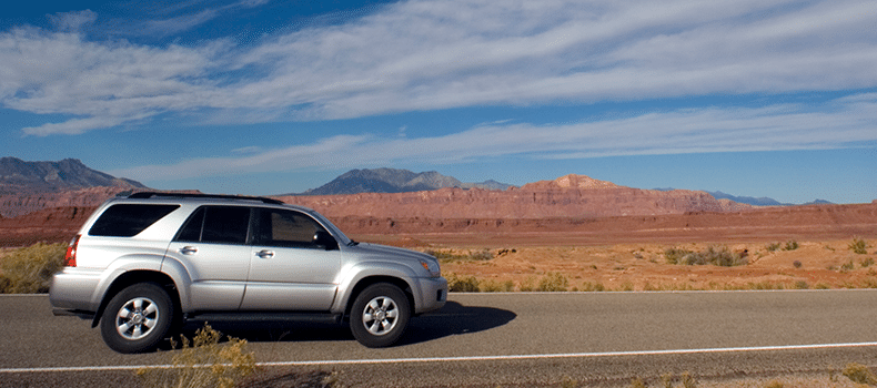 suv driving down desert road